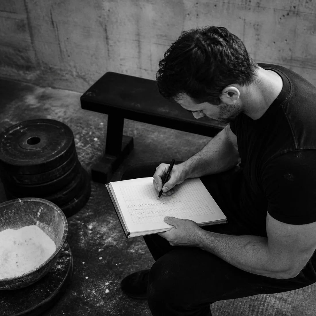 Athlete reviewing a training log beside plates and chalk